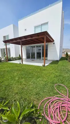 a white building with a red hose in the grass at Casa de Playa de Estreno in Cerro Azul