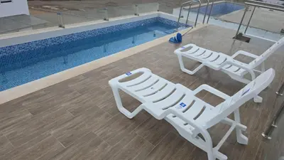two white chairs sitting next to a swimming pool at Casa de Playa de Estreno in Cerro Azul