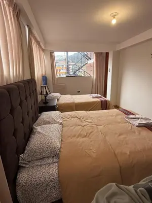 a bedroom with two beds and a chair and a window at Chabela Host in Cusco