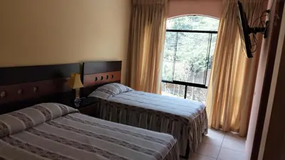 two beds in a hotel room with a window at Tambo II Hotel Campestre in Cieneguilla