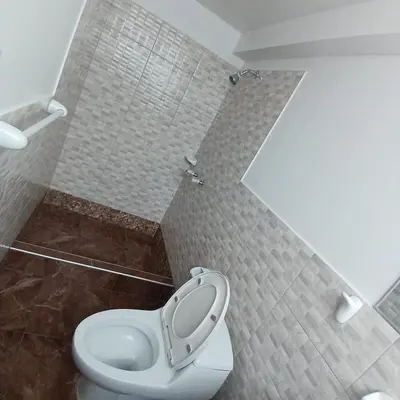 a bathroom with a toilet and a tiled wall at HOSTAl EGIPTO in Ayacucho