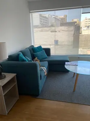 a blue couch in a living room with a table at Urbano Apartments Miraflores Pardo in Lima