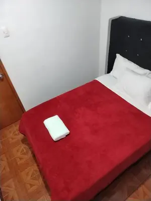 a bed with a red blanket on top of it at Hospedaje Apu San Isidro in Urubamba