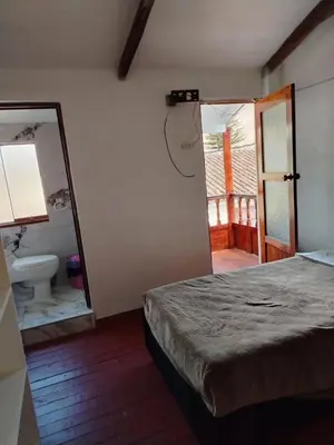 a bedroom with a bed and a bathroom with a mirror at Hospedaje Apu San Isidro in Urubamba