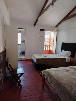 a hotel room with two beds and a bathroom at Hospedaje Apu San Isidro in Urubamba