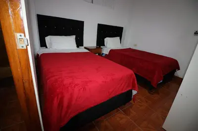 two beds in a room with red sheets at Hospedaje Apu San Isidro in Urubamba