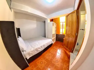 a small bedroom with a bed and a mirror at Hospedaje Apu San Isidro in Urubamba