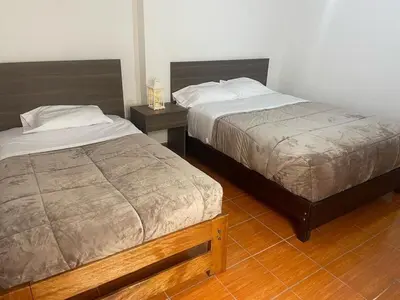 two beds in a bedroom with two night stands at Quechuas in Cusco