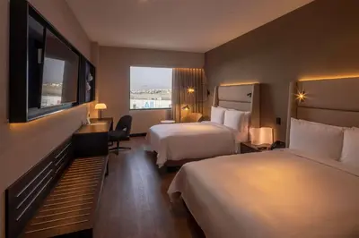 a hotel room with two beds and a flat screen tv at Wyndham Grand Costa Del Sol Lima Airport in Lima