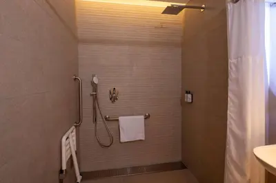 a bathroom with a shower with a white towel at Wyndham Grand Costa Del Sol Lima Airport in Lima