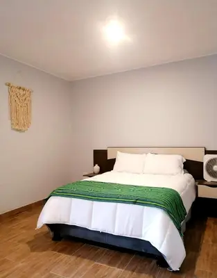 a bedroom with a bed with a green and white blanket at Hotel Sol de Ocucaje #4 in Ica
