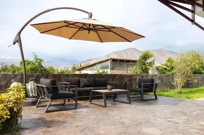 a patio with an umbrella and chairs and a table at Casa campo en Cieneguilla 2,040m2 in Pachacamac