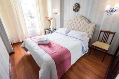 a bedroom with a large bed and a chair at INTI KILLA Hostel in Lima