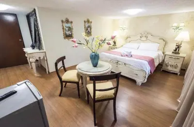 a bedroom with a bed and a table with a vase of flowers at INTI KILLA Hostel in Lima
