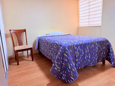 a bedroom with a bed with a blue comforter and a chair at Acogedor Departamento en Lima in Lima