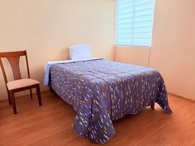 a bedroom with a bed with a blue comforter and a chair at Acogedor Departamento en Lima in Lima
