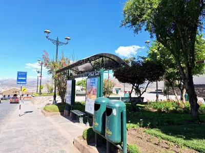 a bus stop with two green trash cans in a park at Jerusalen Inn -Dep 1 in Cusco