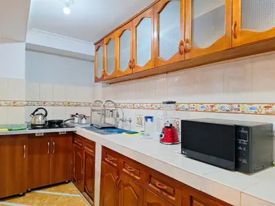 a kitchen with wooden cabinets and a microwave at Jerusalen Inn -Dep 1 in Cusco