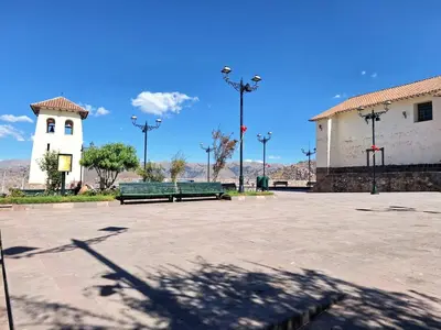a park with two green benches and a white building at Jerusalen Inn-Dep 3 in Cusco