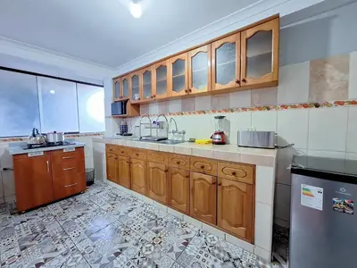 a kitchen with wooden cabinets and a tile floor at Jerusalen Inn-Dep 3 in Cusco