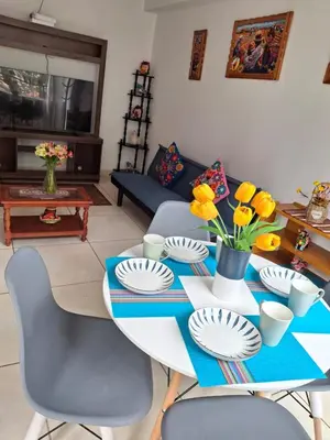 a living room with a table with yellow flowers on it at cusco céntrico in Cusco