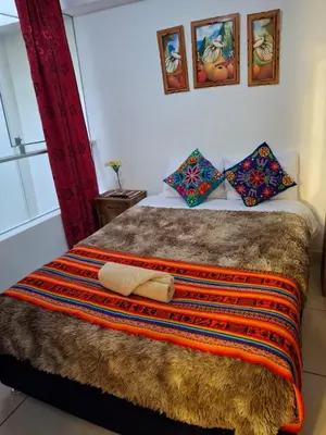 a bed with a brown blanket and pillows on it at cusco céntrico in Cusco
