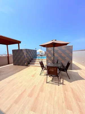 a table and chairs with an umbrella on the beach at Hotel Gboss in Punta Hermosa