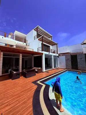 a man standing in a swimming pool next to a house at Casa de Playa en Pulpos Punta Hermosa in Lurín