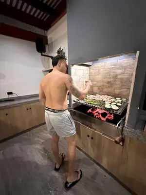 a man standing in a kitchen preparing food in an oven at Casa de Playa en Pulpos Punta Hermosa in Lurín