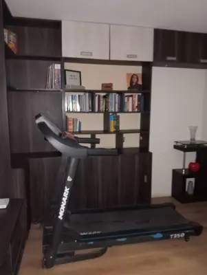 a room with a treadmill and a book shelf at Spacious Apartment - Los Olivos in Lima