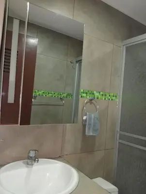 a bathroom with a sink and a shower and a mirror at Spacious Apartment - Los Olivos in Lima