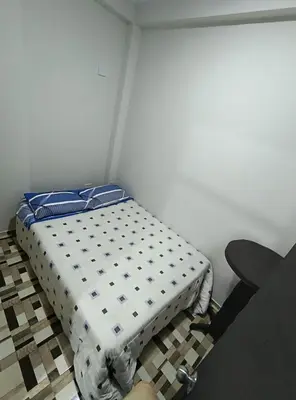 a bed sitting in a corner of a room at Mini departamento acogedor en el centro de Huánuco in Huánuco