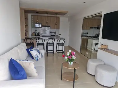 a living room with a couch and a table with flowers at Departamento a un paso de playa Pulpos y Arica in Lurín