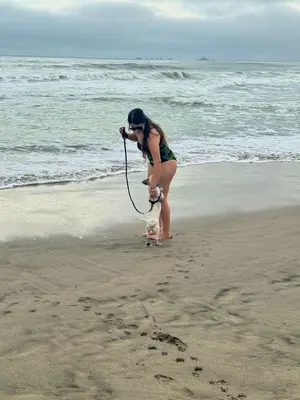 a woman taking a picture of a dog on the beach at Departamento a un paso de playa Pulpos y Arica in Lurín