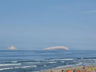 a view of the beach with two islands in the water at Departamento a un paso de playa Pulpos y Arica in Lurín