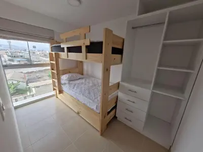 a bedroom with a bunk bed and a window at Departamento a un paso de playa Pulpos y Arica in Lurín