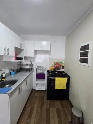 a kitchen with white cabinets and a black stove top oven at Depa moderno - Aeropuerto, San Marcos, Católica in Lima