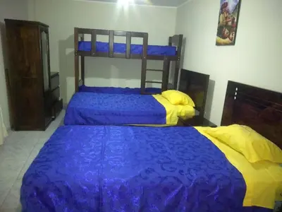 two beds with blue and yellow sheets in a bedroom at Angelica's House Apartments in Lima