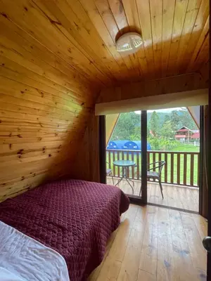 a bedroom in a log cabin with a bed and a patio at Cabaña Alpina Yanesh Haus in Oxapampa