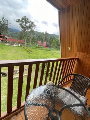 a table and chairs on a balcony with a view of a field at Cabaña Alpina Yanesh Haus in Oxapampa