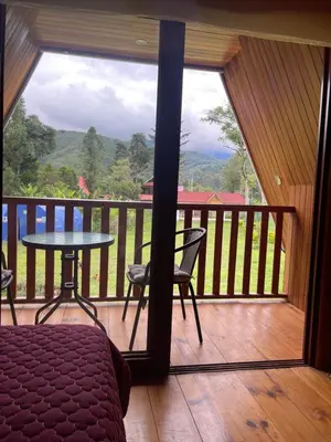 a room with a balcony with a table and a view at Cabaña Alpina Yanesh Haus in Oxapampa