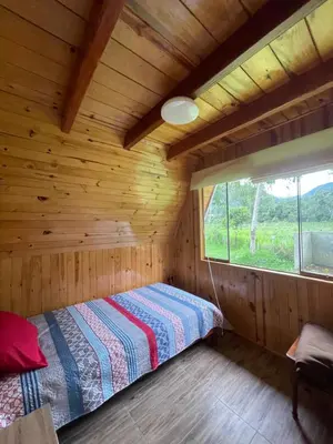 a bed in a wooden room with a window at Cabaña Alpina Yanesh Haus in Oxapampa