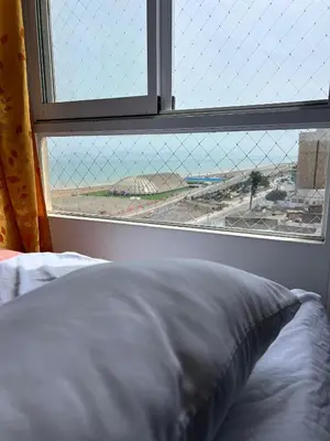 a bed in front of a window with a view at DEPARTAMENTO FRENTE ARENa 1 in Lima