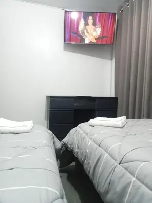 two beds in a room with a tv on the wall at Departamento 2 HABITACIONES 1A in Lima