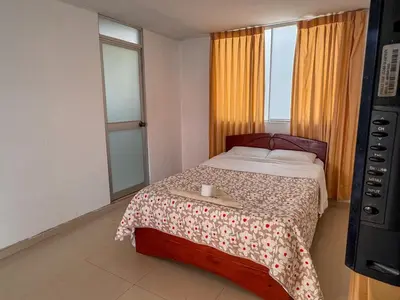 a bedroom with a bed with a table and two windows at Hotel Krammer en San Ramón, Selva Central in San Ramón