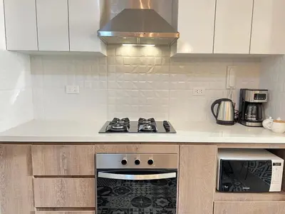 a kitchen with white cabinets and a stove top oven at Design Apartment with city view! - Miraflores in Lima