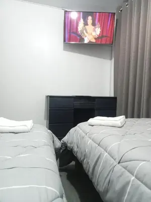 two beds in a room with a tv on the wall at Habitación 02 CAMAS 1C in Lima