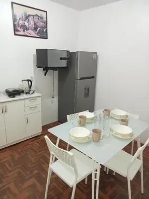 a kitchen with a white table with chairs and a refrigerator at Habitación 02 CAMAS 1C in Lima