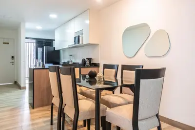 a dining room with a table and chairs and a kitchen at Gardenia by Geko in Lima