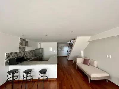 a kitchen and a living room with a couch and stool at Malecón Miraflores Luxury Penthouse in Lima